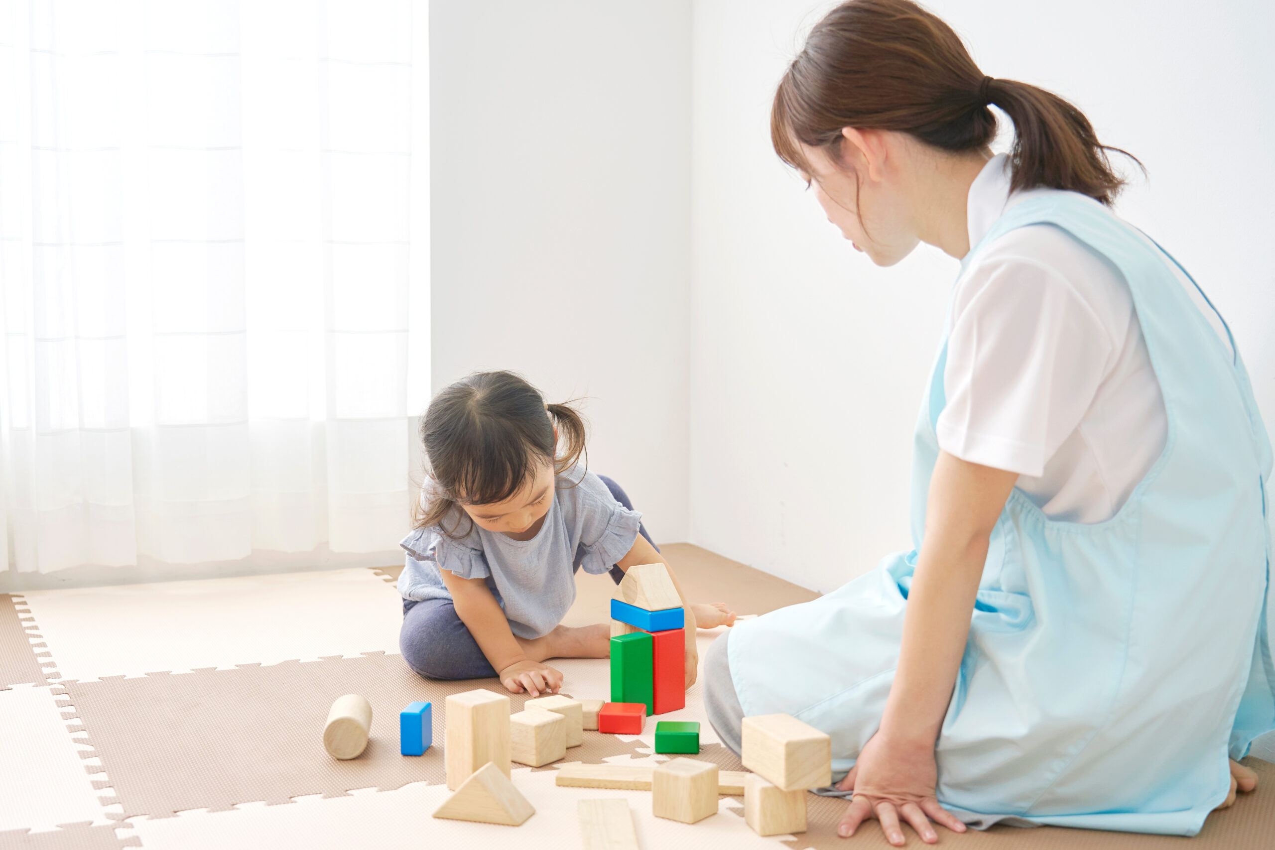 Home 積み木で遊ぶ子供と保育士